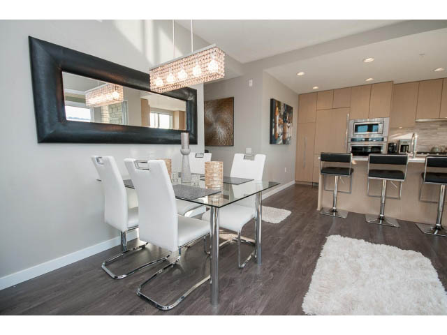 Furnished dining area with modern chairs, glass table, and large mirror. - 203 - 3825 Cate's Landing, North Vancouver