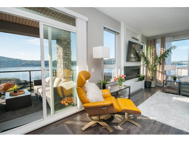 Bright living room with large windows, modern furniture, and a view of the water. - 203 - 3825 Cate's Landing, North Vancouver