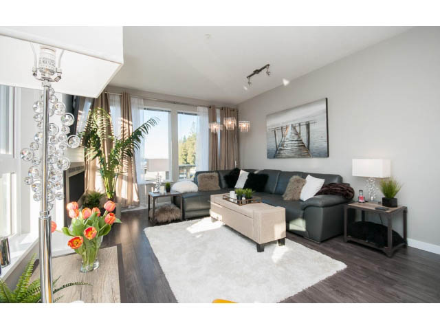 Bright living room with hardwood floors, white fur rug, and city view. - 203 - 3825 Cate's Landing, North Vancouver