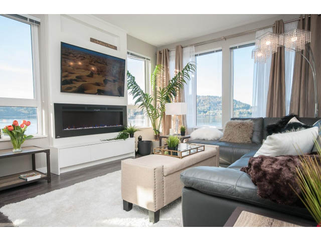 Bright living room with large windows, city view, and modern furnishings. - 203 - 3825 Cate's Landing, North Vancouver