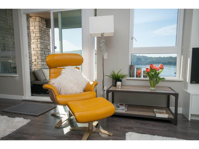 Bright living room with yellow leather chair, hardwood floors, and city view. - 203 - 3825 Cate's Landing, North Vancouver