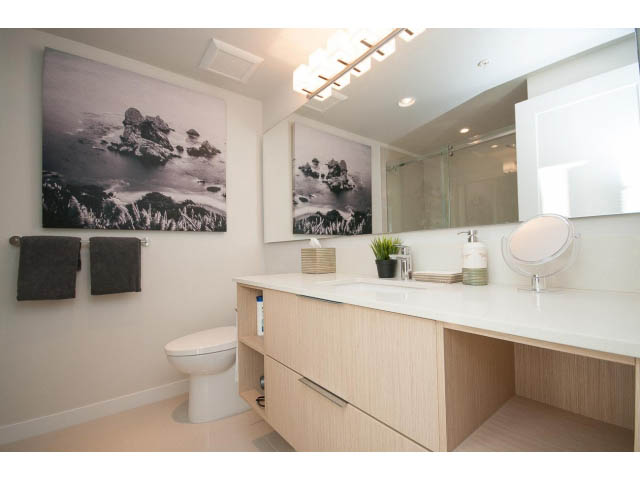 Bright bathroom with light wood vanity, modern fixtures, and black-and-white mountain artwork. - 203 - 3825 Cate's Landing, North Vancouver