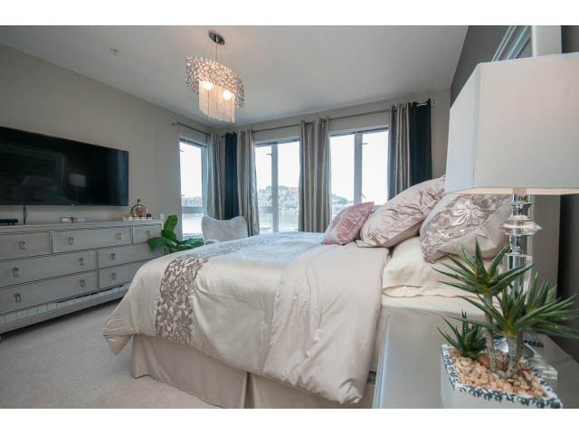 Bright and airy bedroom with large windows, neutral tones, and a cozy bed setup. - 203 - 3825 Cate's Landing, North Vancouver