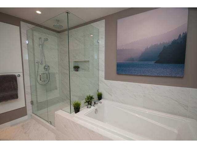 Bright bathroom with marble countertops and a large window showcasing a serene lake view. - 203 - 3825 Cate's Landing, North Vancouver