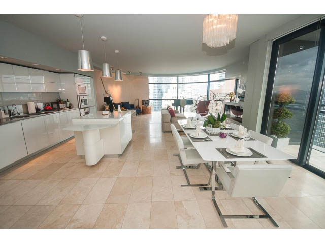Bright kitchen with white countertops and hardwood floors, leading to a spacious dining area with a city view.