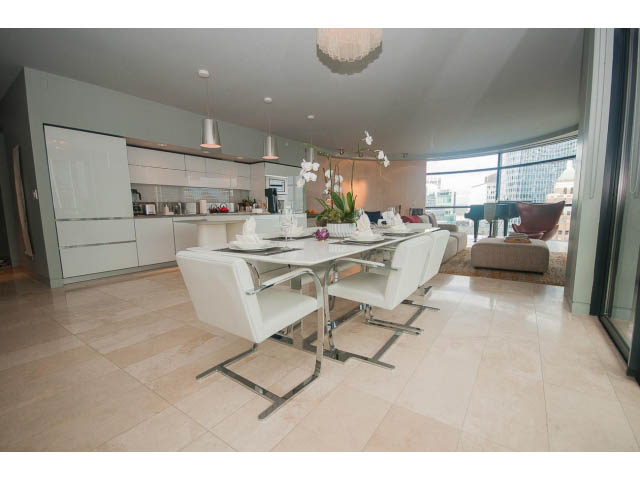 Furnished dining area with modern white chairs, city view, and sleek countertop. - 2301 - 838 W Hastings, Vancouver Downtown