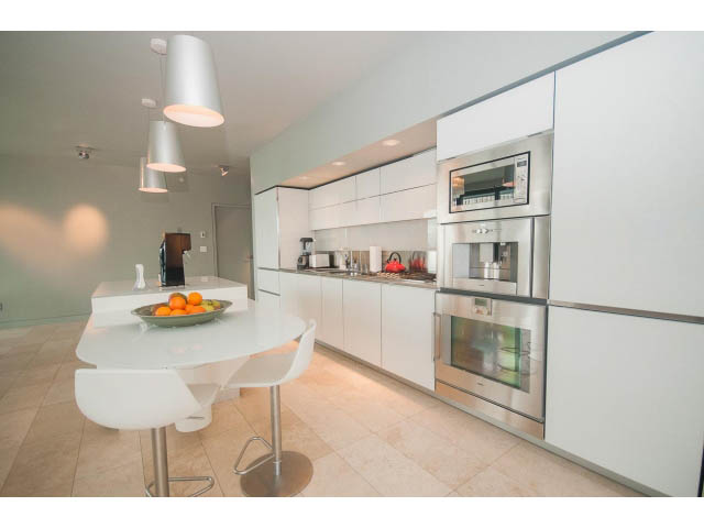 Bright kitchen with white cabinets, stainless steel appliances, and modern pendant lights. - 2301 - 838 W Hastings, Vancouver Downtown