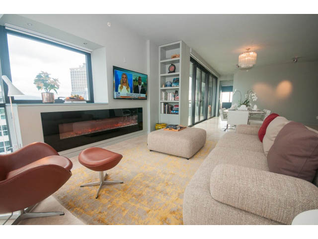 Furnished living room with city view, modern fireplace, and comfortable seating. - 2301 - 838 W Hastings, Vancouver Downtown