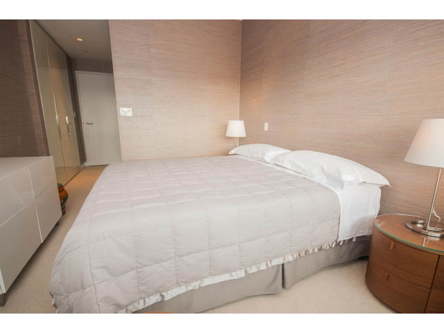 Furnished bedroom with curved beds, white bedding, and modern nightstands. - 2301 - 838 W Hastings, Vancouver Downtown