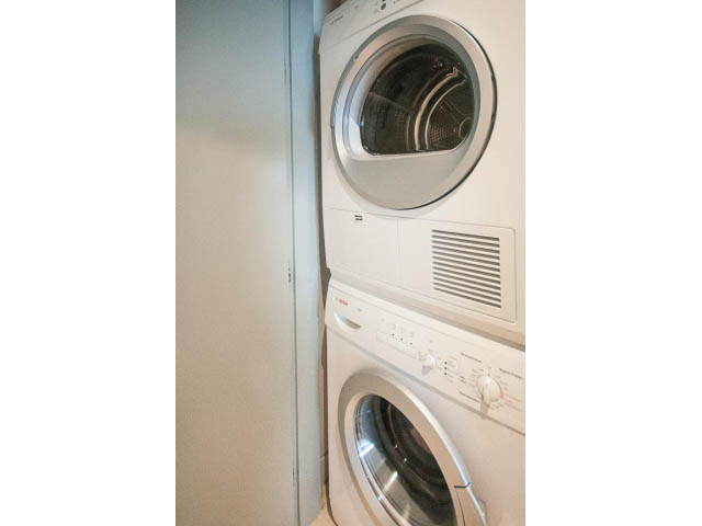 Bright laundry room with stacked washer and dryer, white walls. - 2301 - 838 W Hastings, Vancouver Downtown