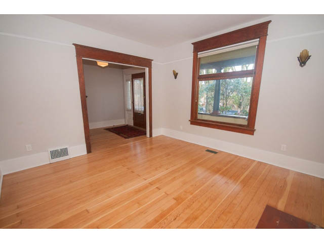 Bright living room with hardwood floors and a large window, leading to another room. - 516 E 10th Ave, Vancouver East Side