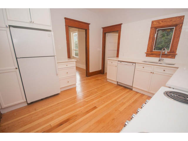 Bright kitchen with white cabinetry, hardwood floors, and a window view. - 516 E 10th Ave, Vancouver East Side