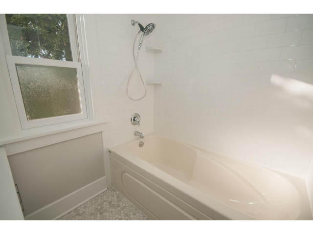 Bright bathroom with white tiles, bathtub, and frosted window. - 516 E 10th Ave, Vancouver East Side