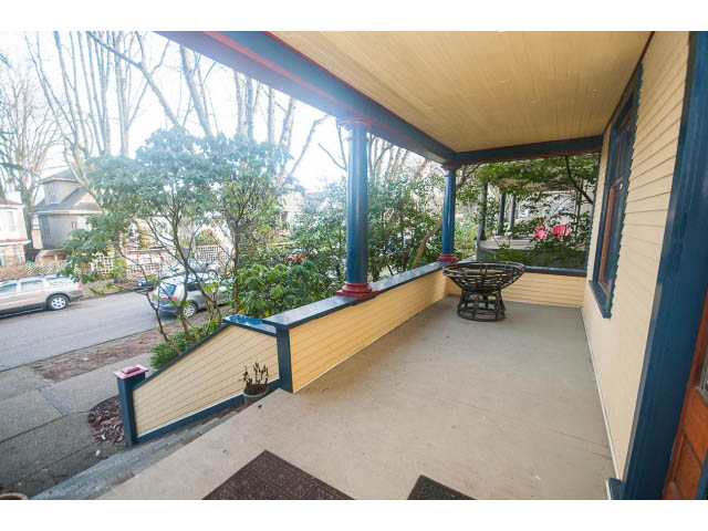 Furnished porch with wooden railings and outdoor seating, surrounded by greenery. - 516 E 10th Ave, Vancouver East Side