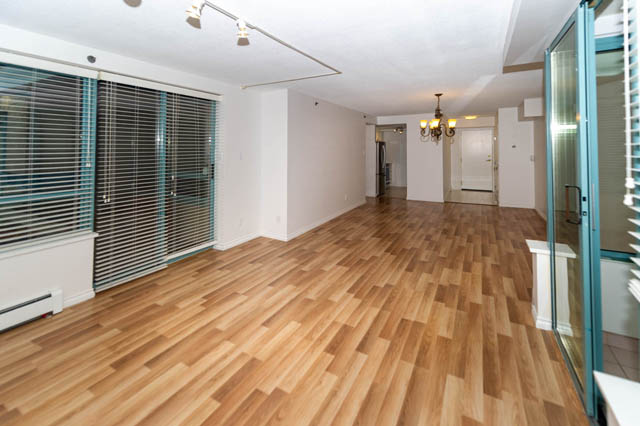 Bright living room with hardwood floors and a chandelier, leading to a hallway. - 204 - 283 Davie Street, Vancouver Downtown