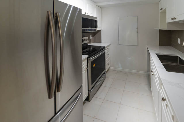 Bright kitchen with white cabinets, stainless steel appliances, and a city view. - 204 - 283 Davie Street, Vancouver Downtown