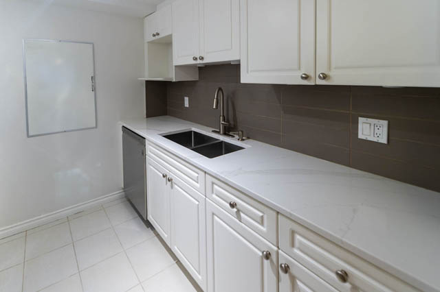 Bright kitchen with white cabinets, dark tile backsplash, and stainless steel sink. - 204 - 283 Davie Street, Vancouver Downtown