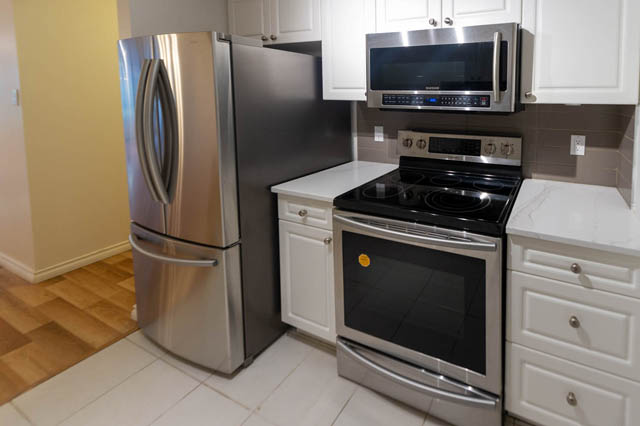 Bright kitchen with stainless steel appliances, white cabinets, and hardwood floors. - 204 - 283 Davie Street, Vancouver Downtown