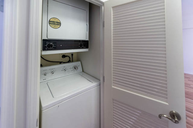 Laundry room with stacked washer and dryer, white blinds. - 204 - 283 Davie Street, Vancouver Downtown