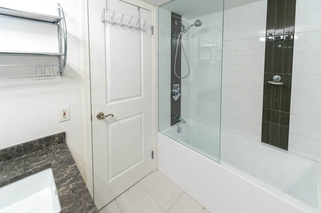 Bright bathroom with white tiles, glass shower, and marble countertop. - 204 - 283 Davie Street, Vancouver Downtown