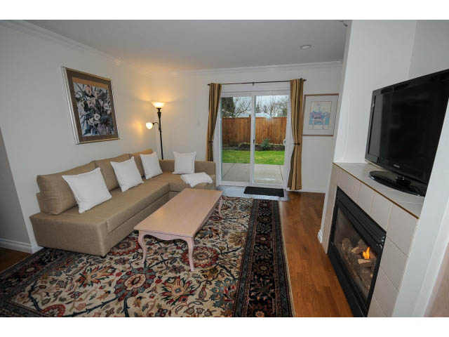 Living room with hardwood floors, fireplace, and sliding glass doors leading to a backyard. - 1397 Tatlow Avenue, North Vancouver