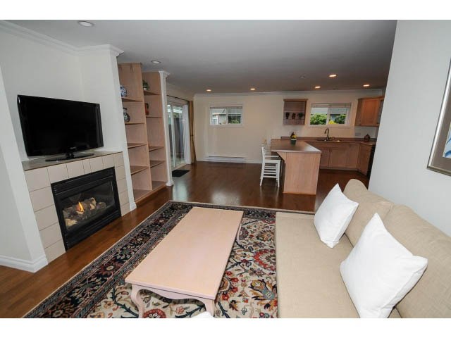 Open-concept living area with hardwood floors, modern kitchen, and cozy seating. - 1397 Tatlow Avenue, North Vancouver