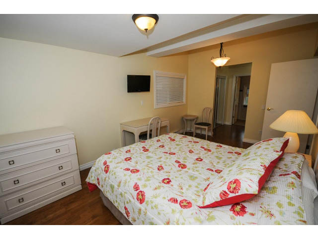 Spacious bedroom with floral bedding and hardwood floors. - 1397 Tatlow Avenue, North Vancouver