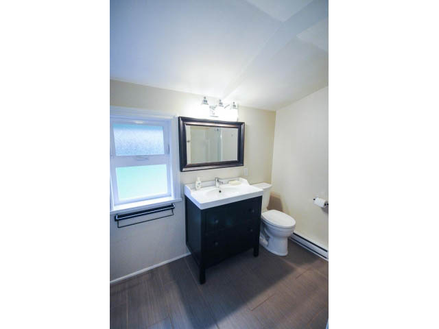Bright bathroom with dark vanity, white walls, and a window. - 1397 Tatlow Avenue, North Vancouver