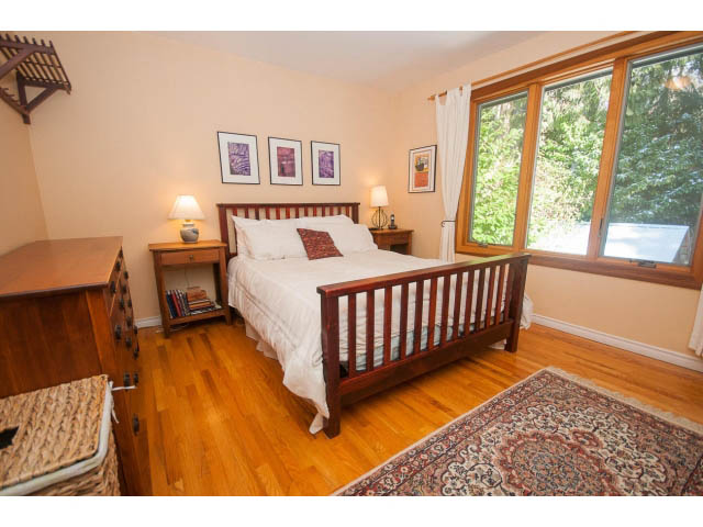 Bright bedroom with hardwood floors, large windows, and a cozy bed setup. - 2972 Wembley Dr, North Vancouver