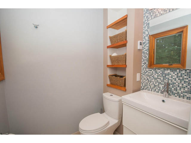 Bathroom with white countertop, tiled backsplash, and wooden shelves. - 2972 Wembley Dr, North Vancouver