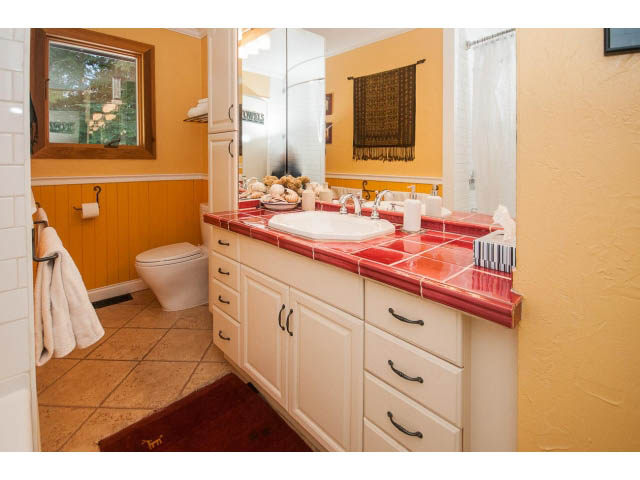 Bright bathroom with orange and white countertops, tiled floor, and a window view. - 2972 Wembley Dr, North Vancouver
