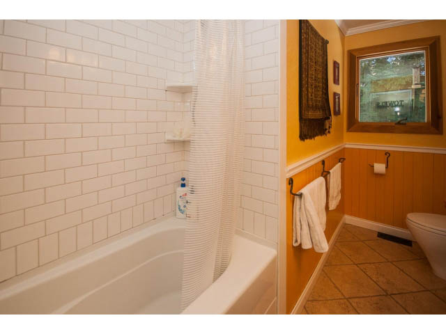 Bright bathroom with white subway tile, wooden accents, and a window view. - 2972 Wembley Dr, North Vancouver