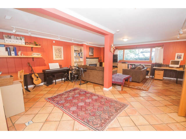 Spacious living room with tiled floors, red walls, and a red rug. - 2972 Wembley Dr, North Vancouver