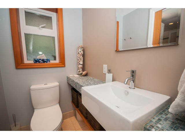 Furnished bathroom with white sink, mirror, and wooden accents. - 2972 Wembley Dr, North Vancouver