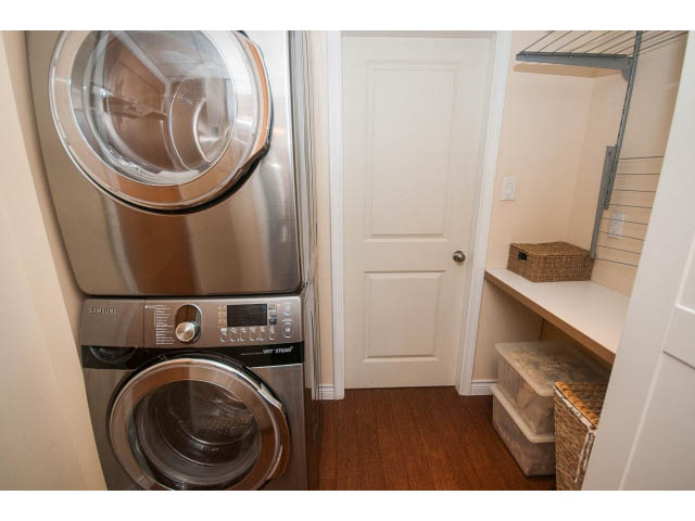Bright laundry room with stainless steel appliances, hardwood floors, and storage baskets. - 2972 Wembley Dr, North Vancouver