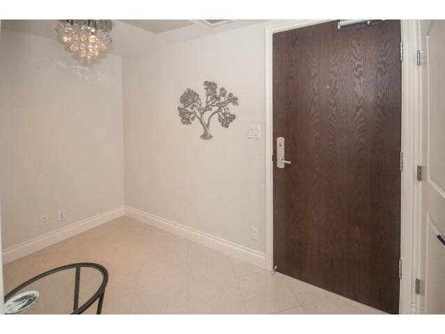 Furnished den with wooden door and wall art, light beige walls and flooring. - 1008-199 Victory Ship Way, North Vancouver