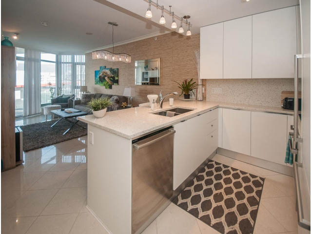 Bright kitchen with white cabinets, granite countertops, and a city view. - 1008-199 Victory Ship Way, North Vancouver