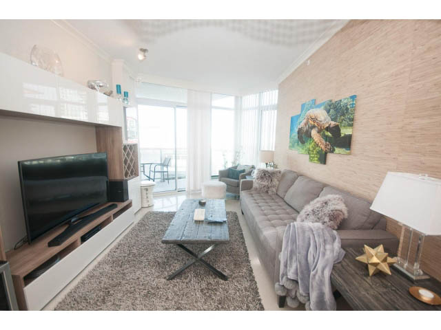 Furnished living room with modern decor, large window, and cozy seating. - 1008-199 Victory Ship Way, North Vancouver