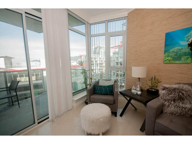 Bright living room with city view, modern decor, and cozy seating. - 1008-199 Victory Ship Way, North Vancouver