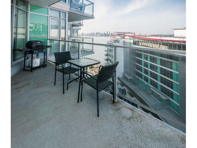 Furnished balcony with outdoor table, chairs, and grill, overlooking cityscape and water. - 1008-199 Victory Ship Way, North Vancouver