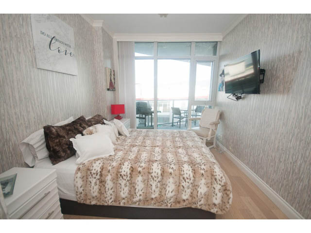 Furnished 1-bedroom + den with cozy bedding, hardwood floors, and a large window offering a city view. - 1008-199 Victory Ship Way, North Vancouver