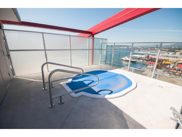 Bright balcony with city view, furnished lounge chairs, and clear glass railings. - 1008-199 Victory Ship Way, North Vancouver