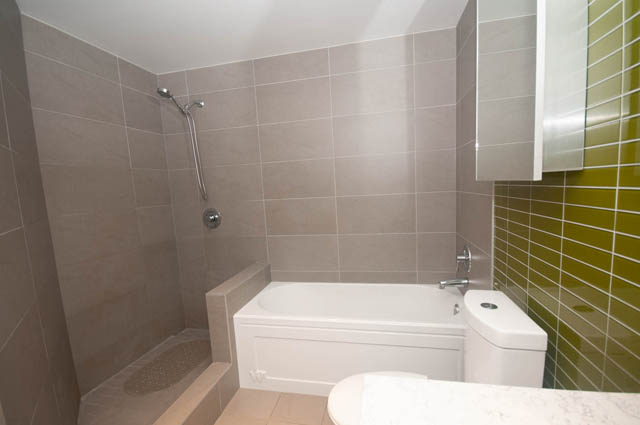 Furnished bathroom with modern shower, green accent wall, and white countertop. - 3806 - 128 Cordova St W, Vancouver Downtown