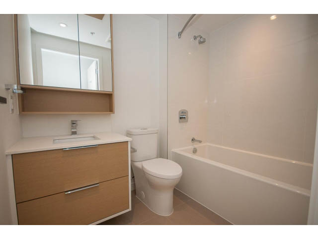 Bright bathroom with modern sink, wooden cabinets, and a bathtub/shower combo. - 1108 - 1661 Quebec St, Vancouver West Side