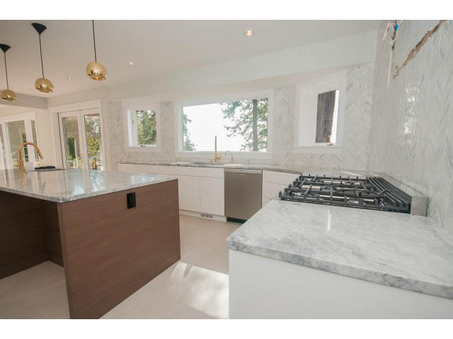 Bright kitchen with white marble countertops, modern pendant lights, and large windows. - 6018 Gleneagles Place, West Vancouver