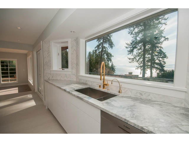 Bright kitchen with marble countertops and a view of the forest. - 6018 Gleneagles Place, West Vancouver