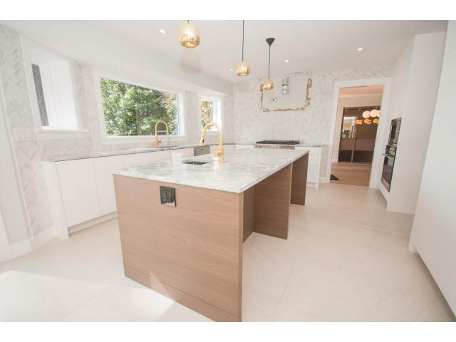Bright kitchen with white marble countertops, wooden island, and pendant lights. - 6018 Gleneagles Place, West Vancouver
