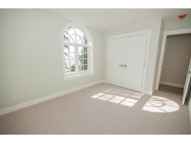 Spacious bedroom with arched window and built-in bench, light-filled. - 6018 Gleneagles Place, West Vancouver