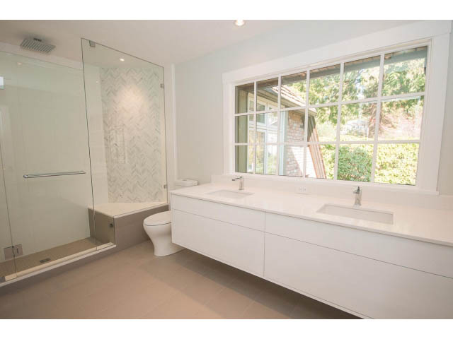 Bright bathroom with white vanity, large window, and glass shower. - 6018 Gleneagles Place, West Vancouver