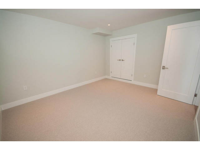 Bright bedroom with white walls, carpeted floor, and double doors. - 6018 Gleneagles Place, West Vancouver